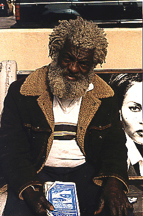 Man with curly white hair and beard holding a book